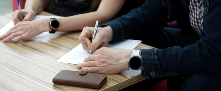 Adult man and woman fill out the forms. Concept of divorce proceedings, signing a marriage contract, lease agreement or notarized power of attorney. No face. Close-up