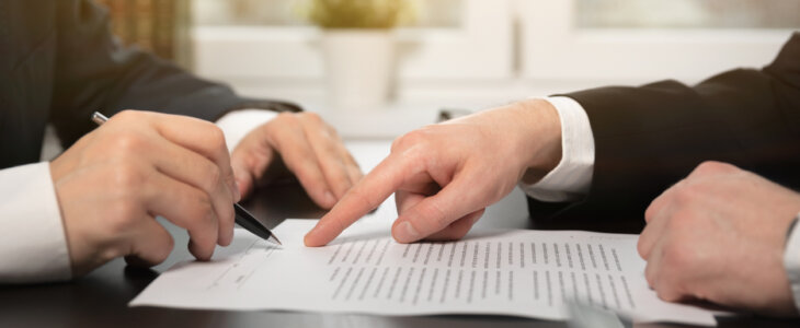 Two people reviewing and signing a legal document at a desk.