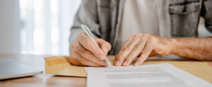 senior man open mail letter sign document envelope while sit at the table at home receiving bank statement loan approval contract or business insurance news invitation