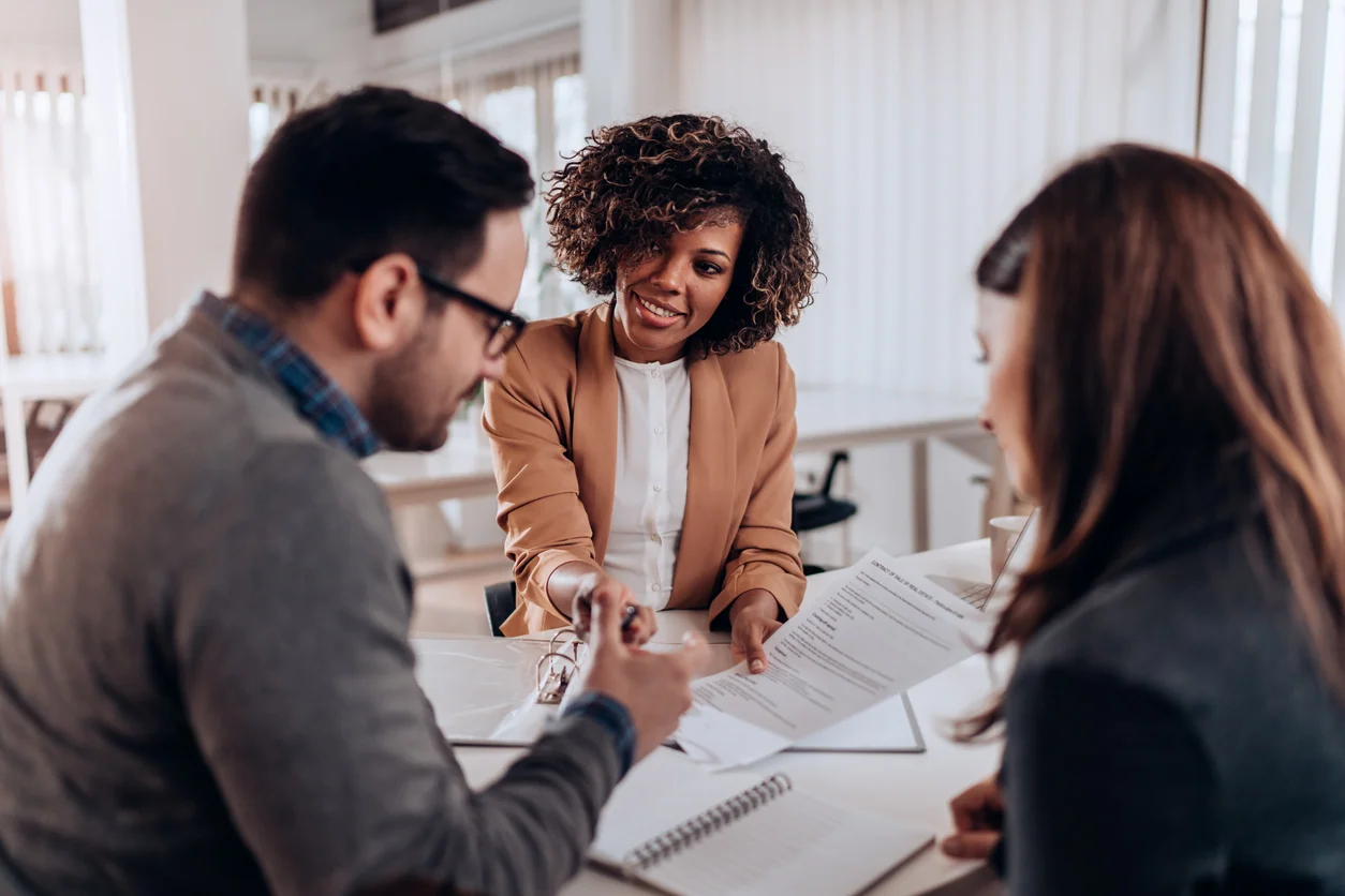 Couple sitting at the desk in the law office and signing business agreement